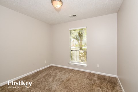 a bedroom with carpet and a large window