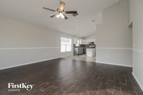A spacious room with wooden flooring and a ceiling fan.