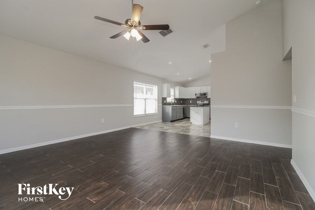 A spacious room with wooden flooring and a ceiling fan.