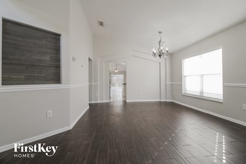 A spacious room with wooden floors and a chandelier.