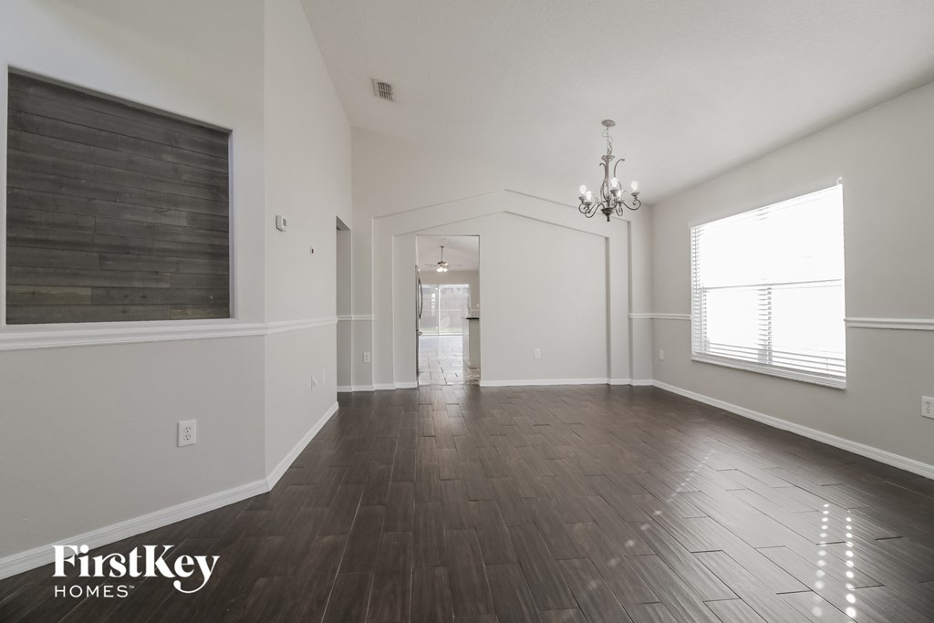 A spacious room with wooden floors and a chandelier.