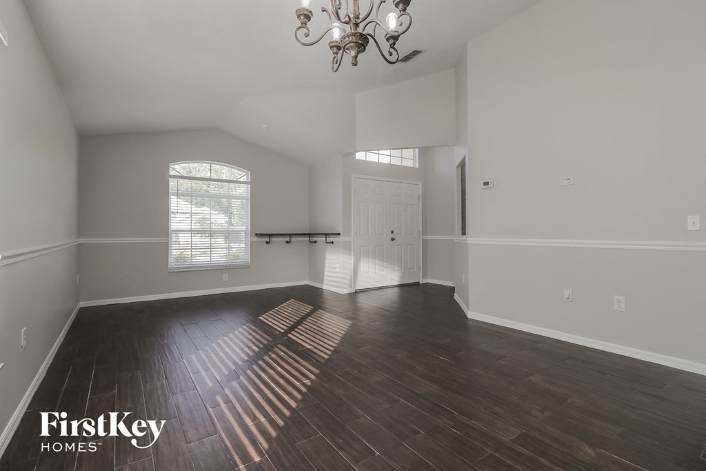 A large empty room with wooden floors and a chandelier.