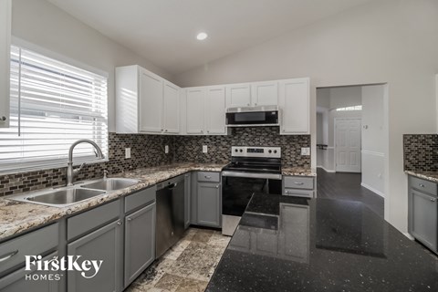 A kitchen with a black granite countertop and a stove top oven.