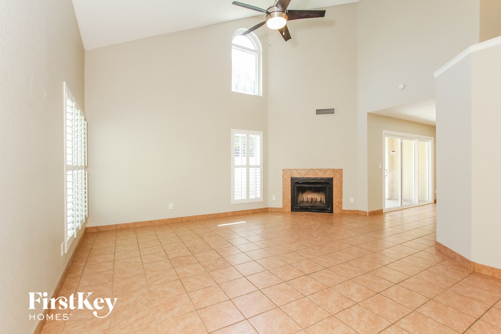 an empty living room with a fireplace and a ceiling fan