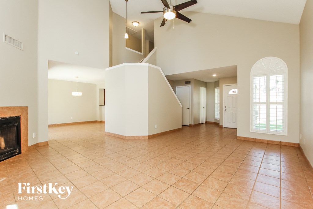 an empty living room with a fireplace and a ceiling fan