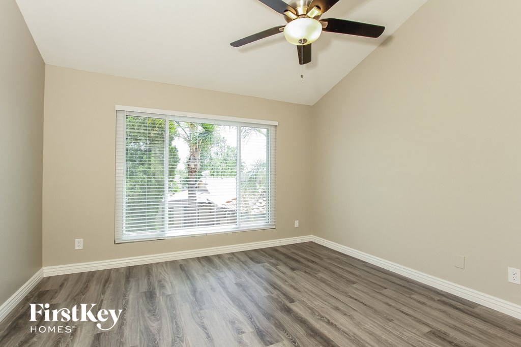 an empty bedroom with a large window and a ceiling fan
