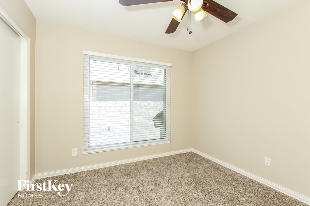 a bedroom with a large window and a ceiling fan