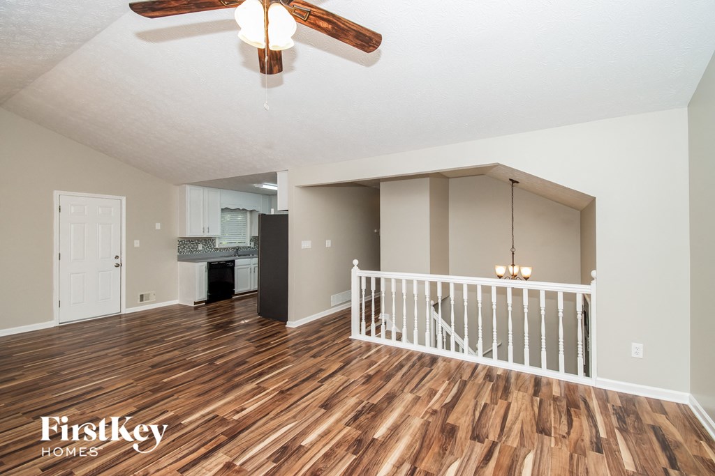 A spacious room with wooden floors and a ceiling fan.