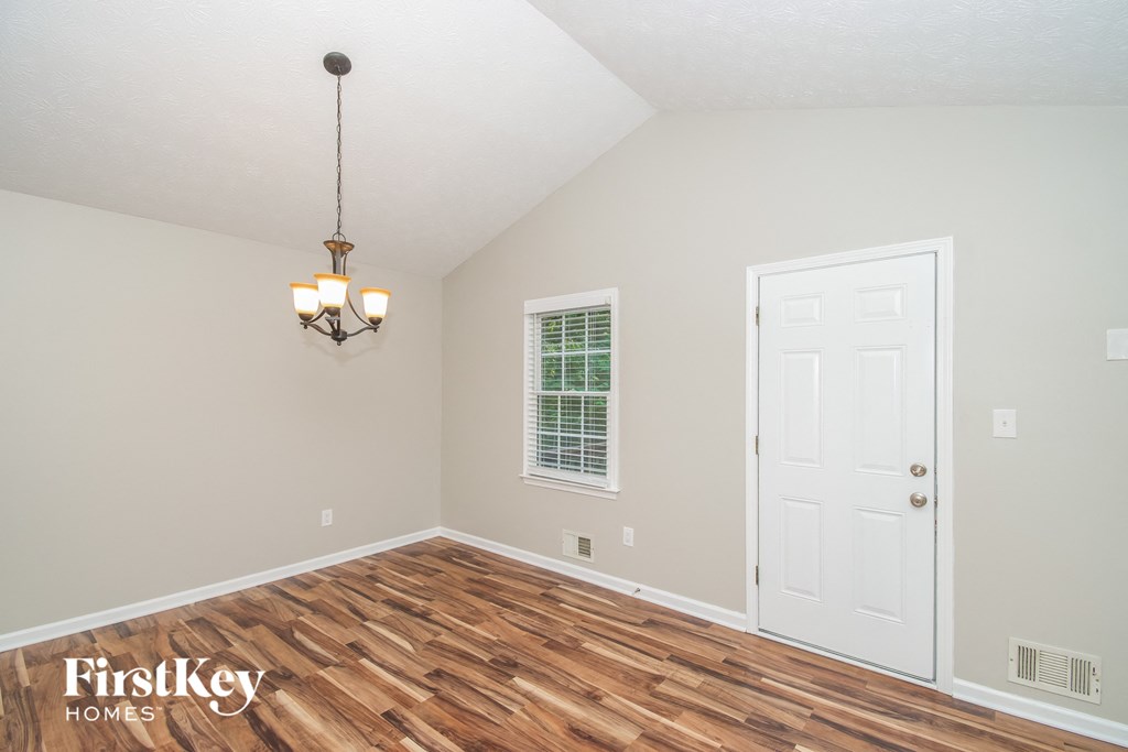A room with a wooden floor and a chandelier hanging from the ceiling.