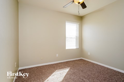 a bedroom with carpet and a window and a ceiling fan