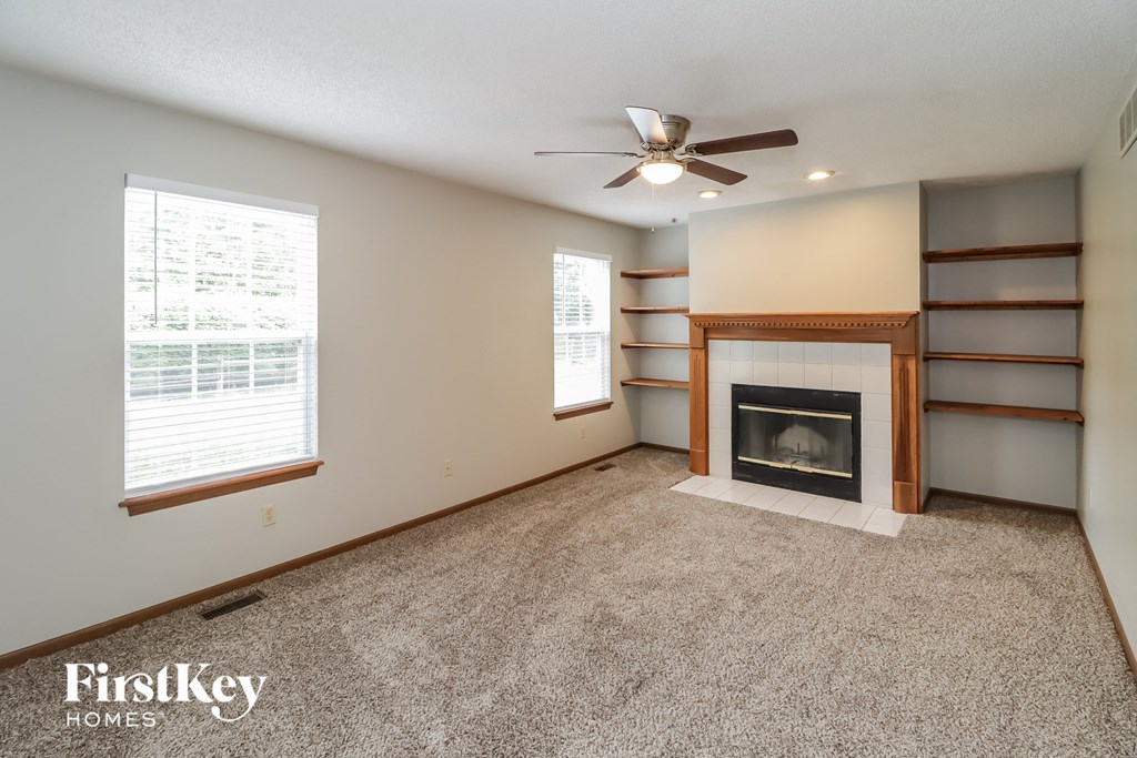 A living room with a fireplace and a ceiling fan.