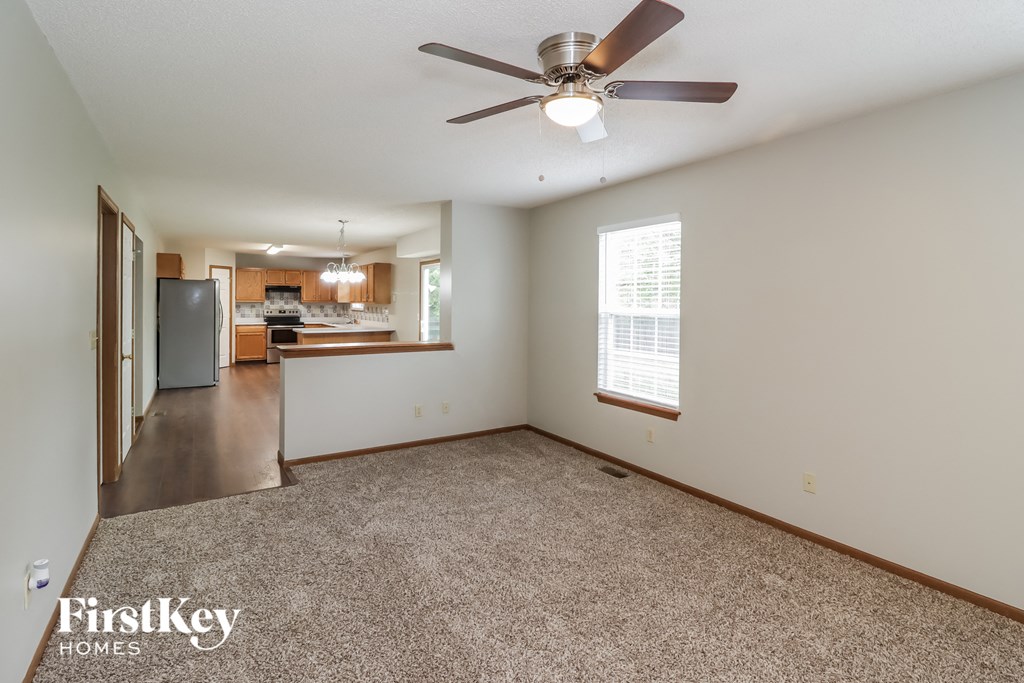 A spacious room with a ceiling fan and a window with blinds.