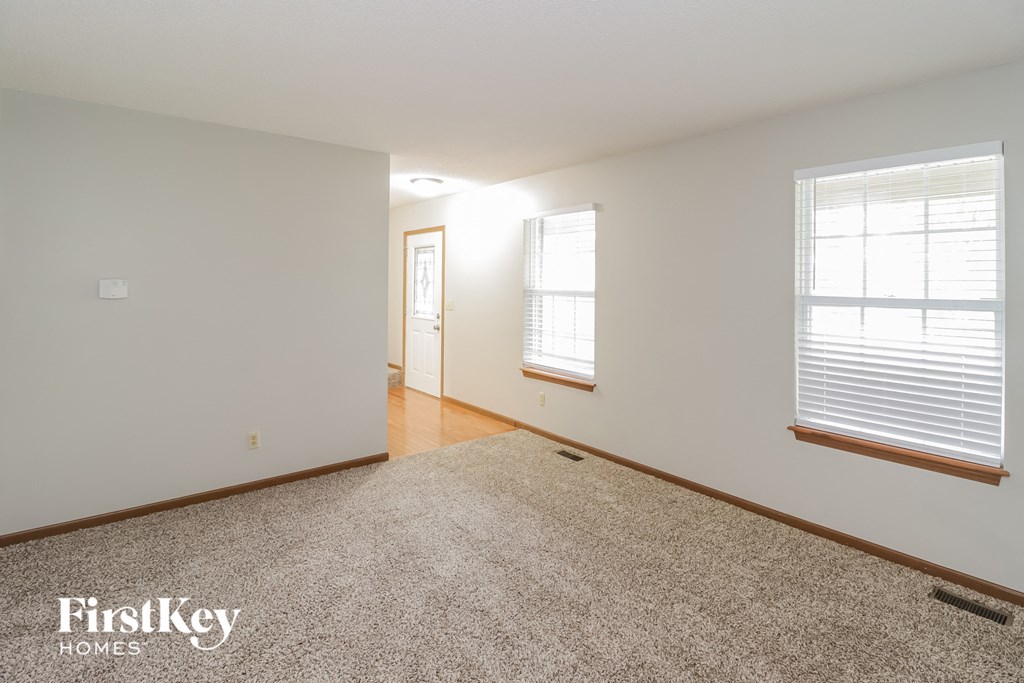 A carpeted room with a door and a window.