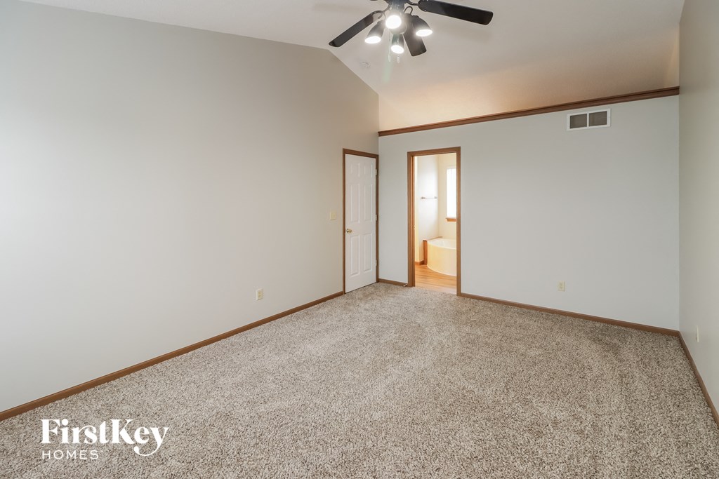 A spacious room with a carpeted floor and a ceiling fan.