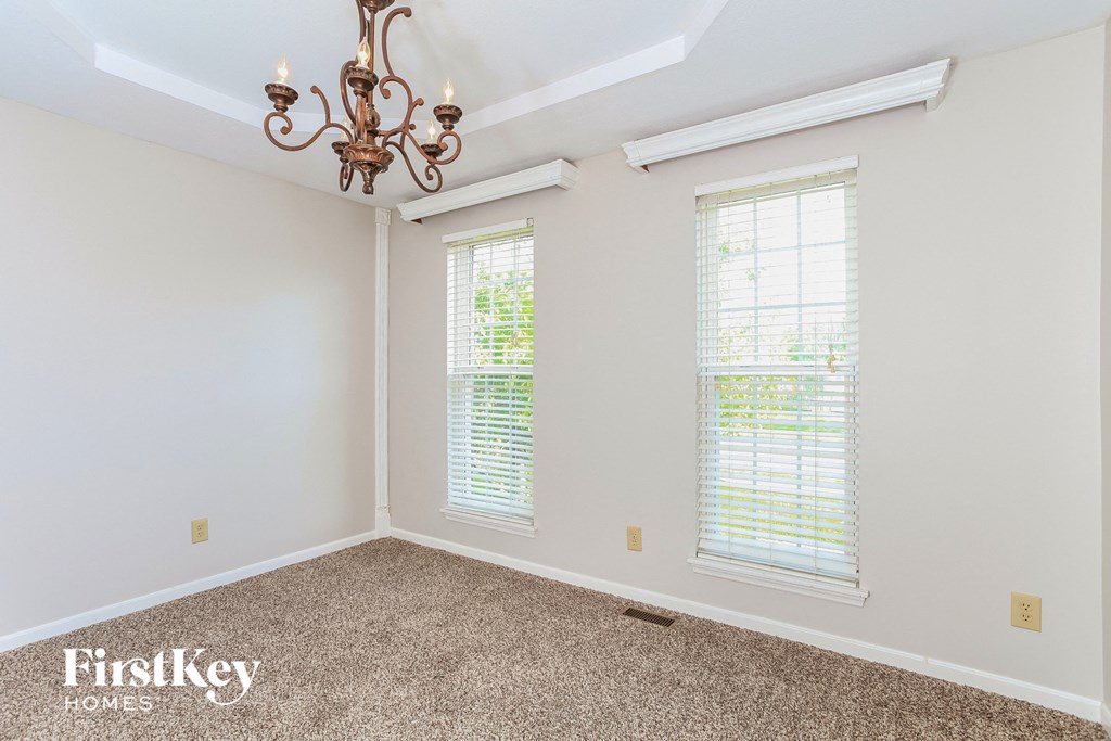 A room with a chandelier and two windows.