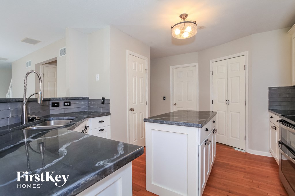 A kitchen with a marble countertop and white cabinets.