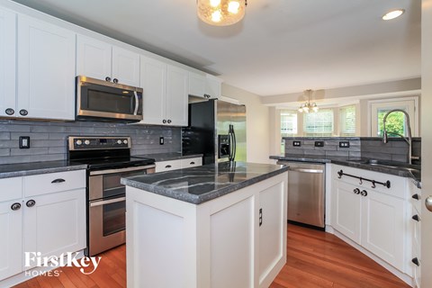 A kitchen with white cabinets and a black stove top oven.