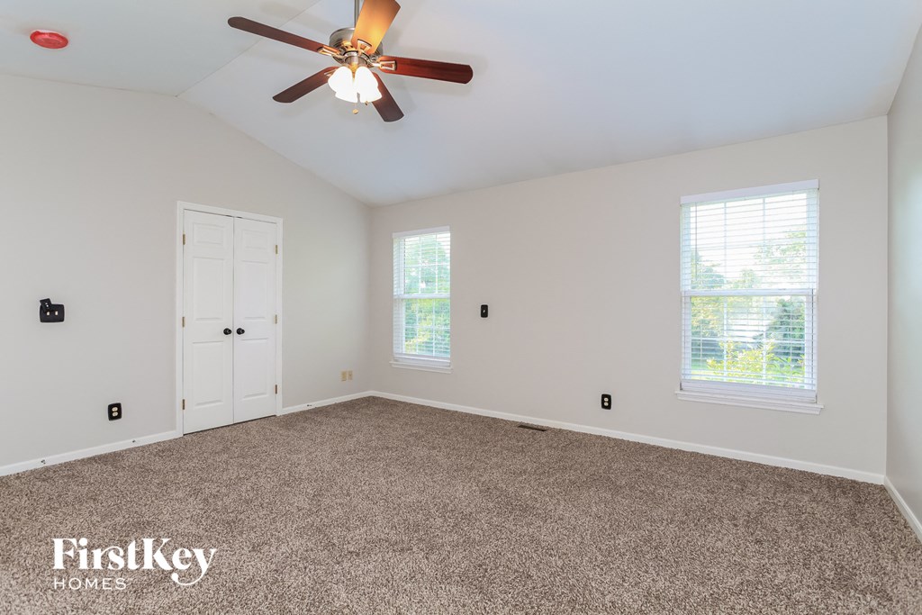 A room with a ceiling fan and two windows.