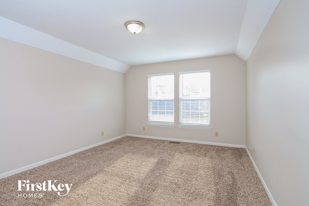 A room with a carpeted floor and two windows.