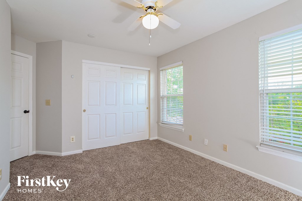 A room with a carpet floor, a ceiling fan, and a window with blinds.