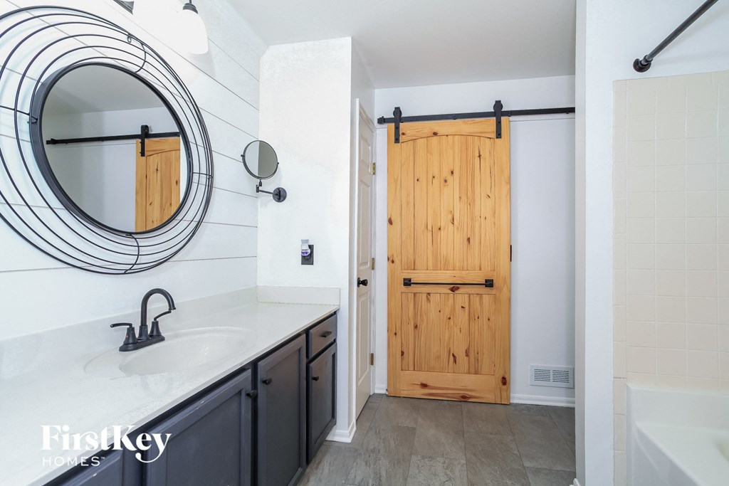 A bathroom with a round mirror and a wooden door.