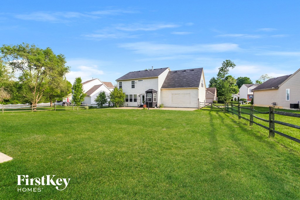 A grassy field with a fence and a house in the background.