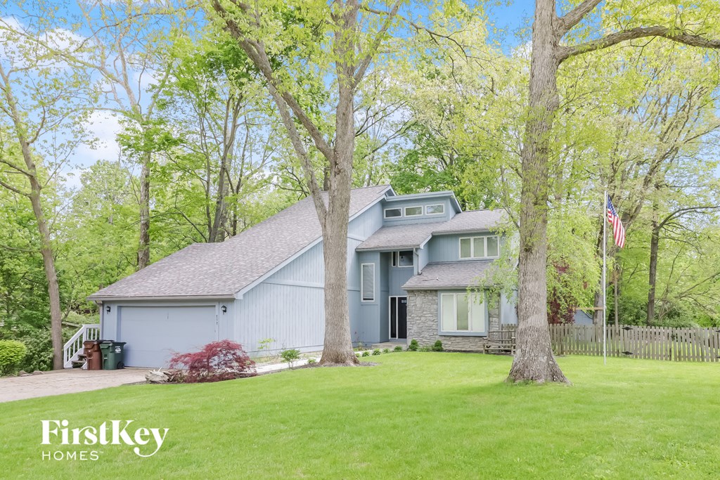 a blue house with a lawn and trees