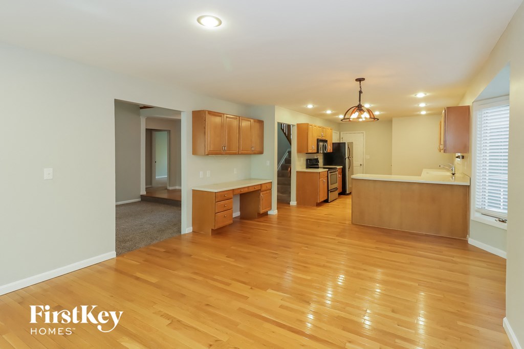 an empty living room and kitchen with wood flooring