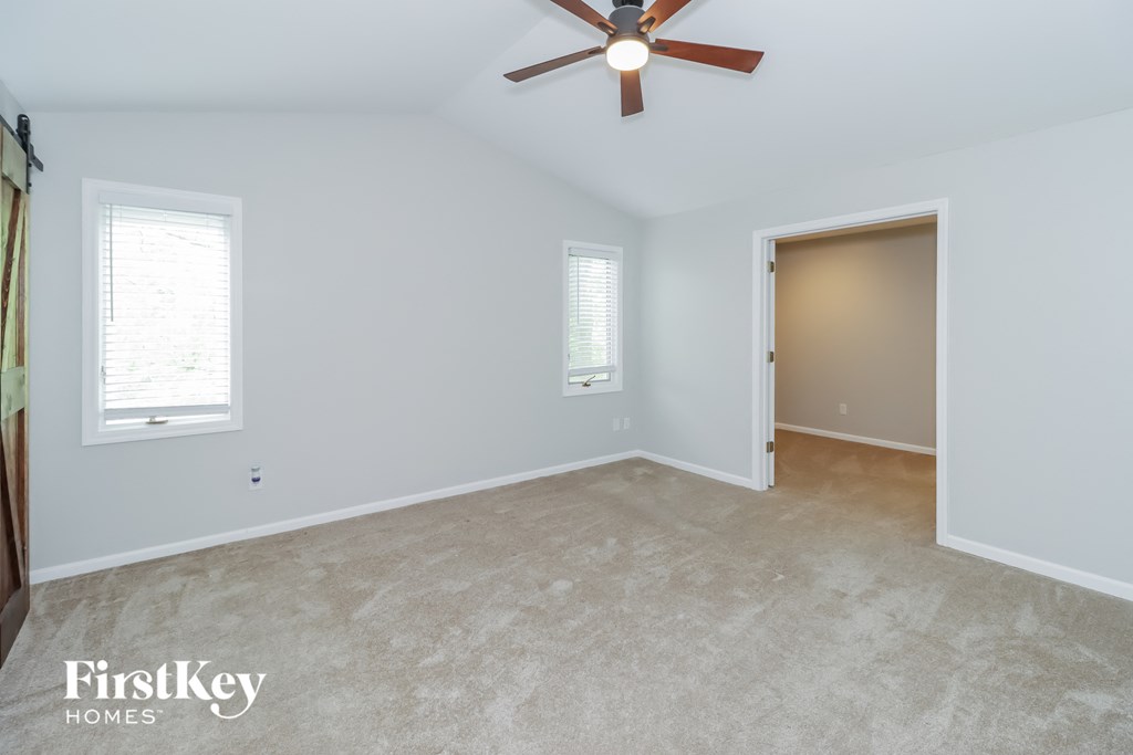a bedroom with white walls and a ceiling fan