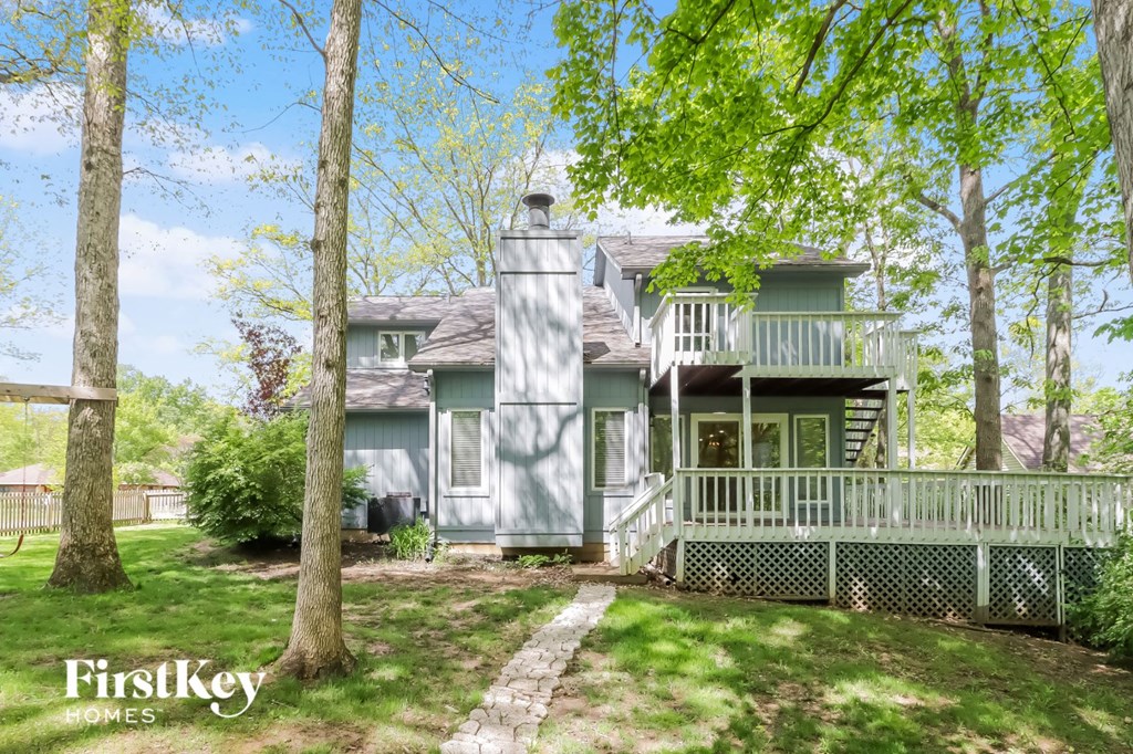 front view of the house with deck and trees