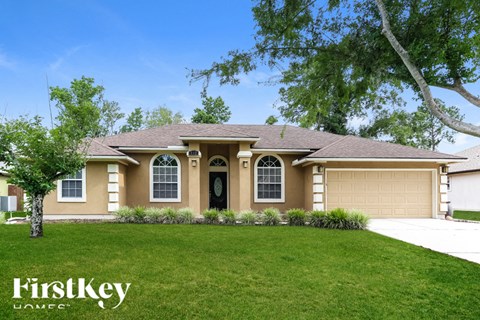 A house with a brown roof and a black door is surrounded by greenery.