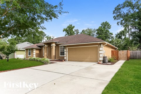 A house with a brown roof and tan walls has a garage door that is open.