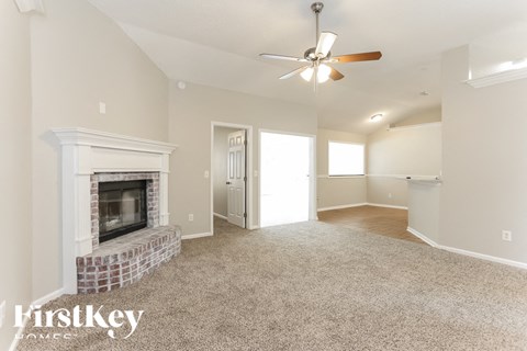 A spacious living room with a fireplace and a ceiling fan.