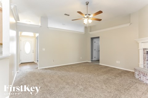 A spacious room with a ceiling fan and beige walls.