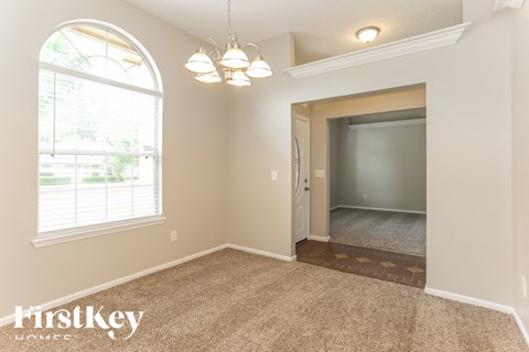 A room with a carpeted floor and a large arched window.