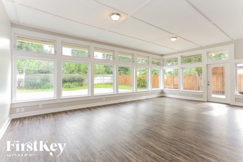 A spacious room with wooden floors and large windows.