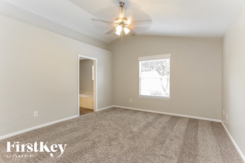 A spacious room with a carpeted floor and a ceiling fan.