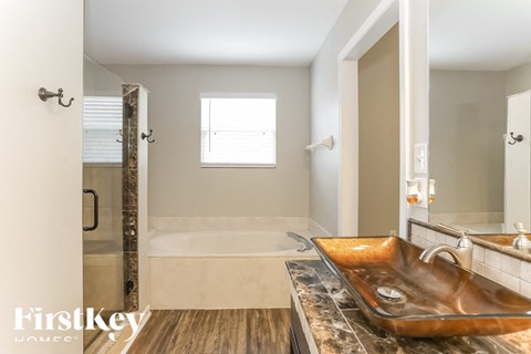 A bathroom with a large sink and a walk-in shower.