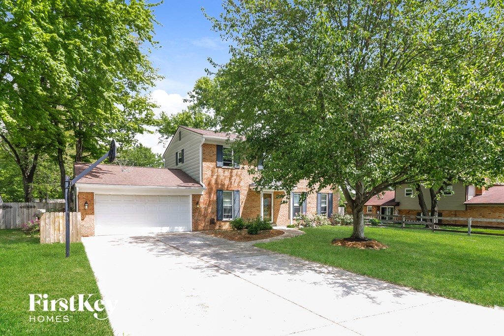a house with a driveway and trees in front of it