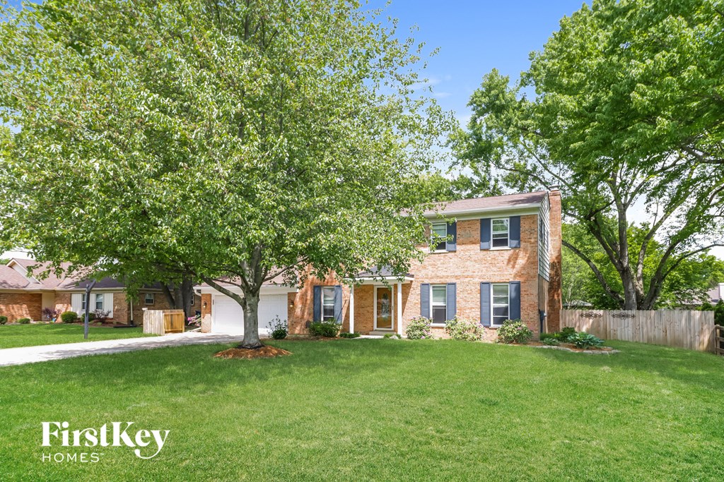 front view of a brick house with trees and grass
