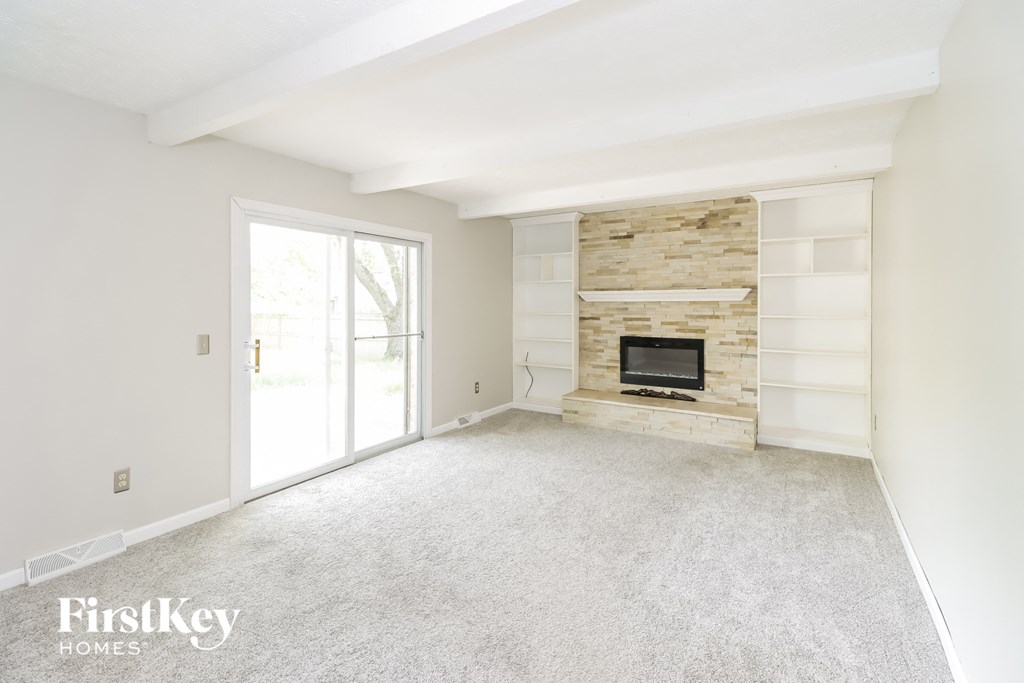 an empty living room with a fireplace and a glass door