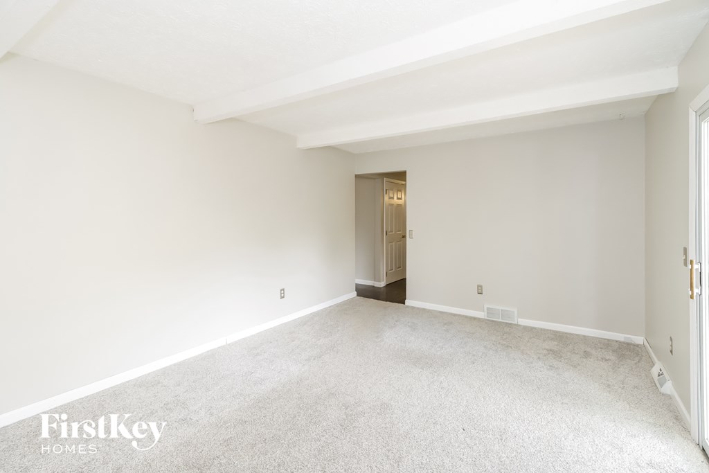 the living room and dining room of an empty home with white walls and carpet