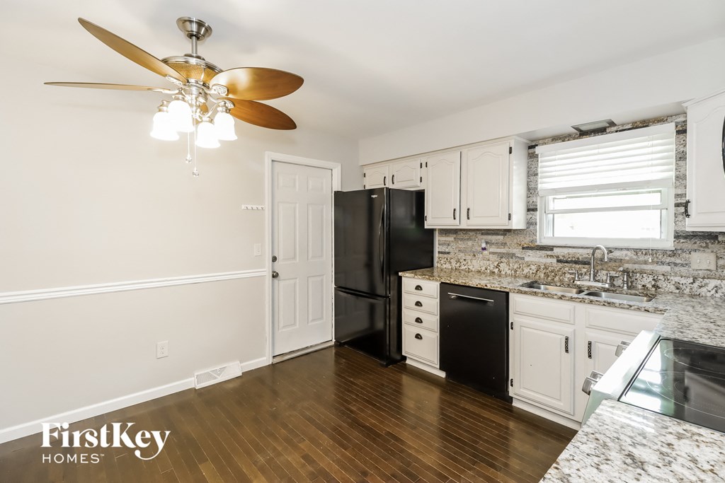 a kitchen with white cabinets and a black refrigerator