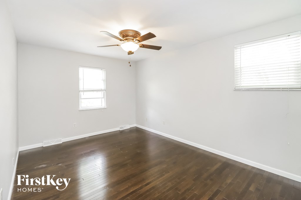 a bedroom with white walls and wood floors and a ceiling fan