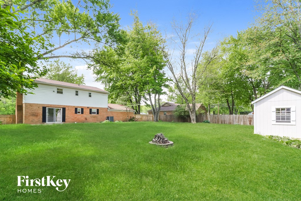 a backyard with green grass and a white house and a yard with a tree