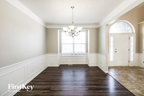 an empty dining room with a window and a chandelier