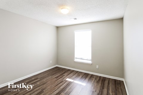 the living room of an apartment with wood flooring and a window