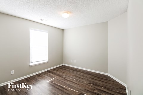 the upstairs bedroom with hardwood flooring and a window