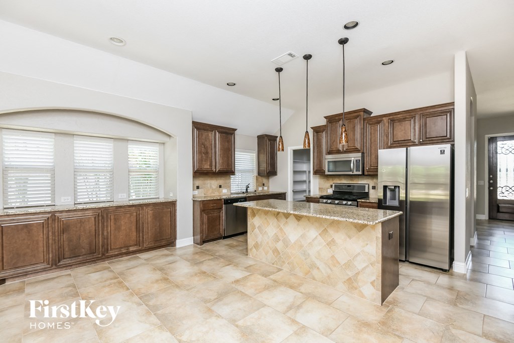 a kitchen with wooden cabinets and a marble counter top