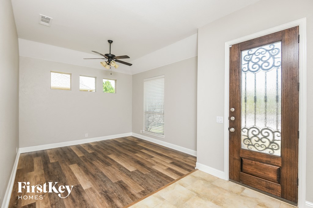 an empty room with a wooden door and a ceiling fan
